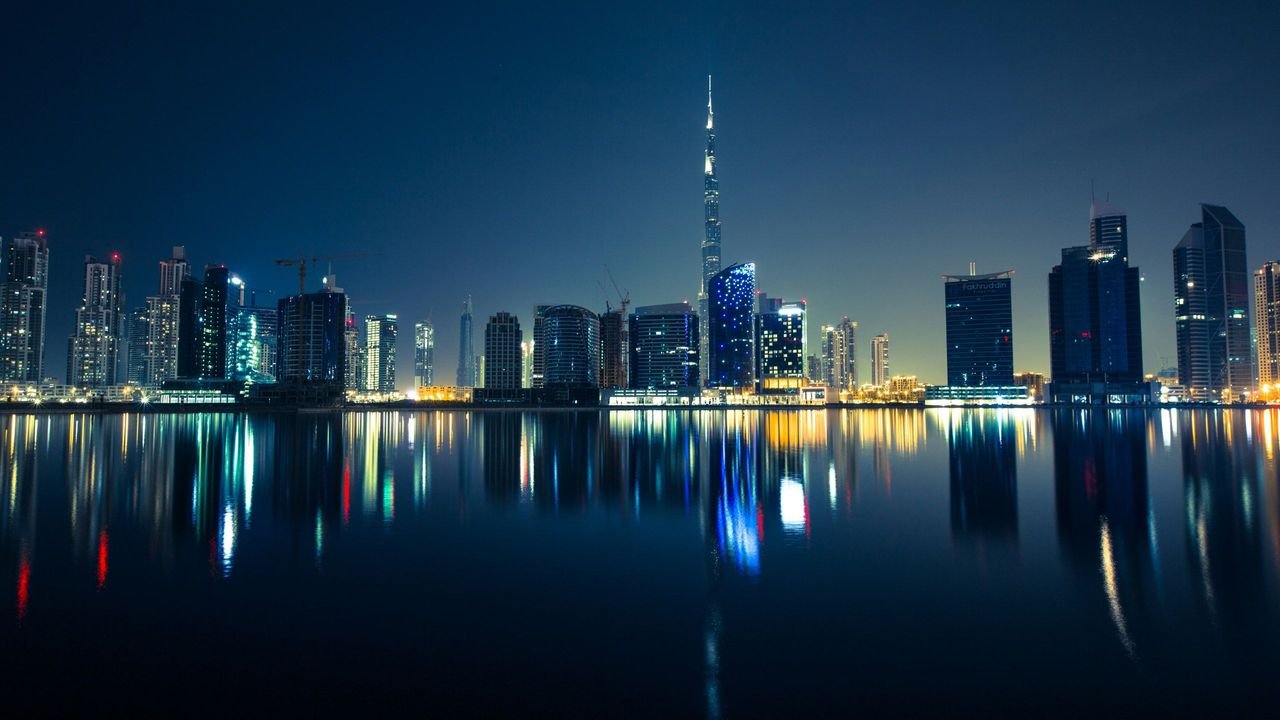 The Burj Khalifa and Business Bay towers mirrored in still water at night